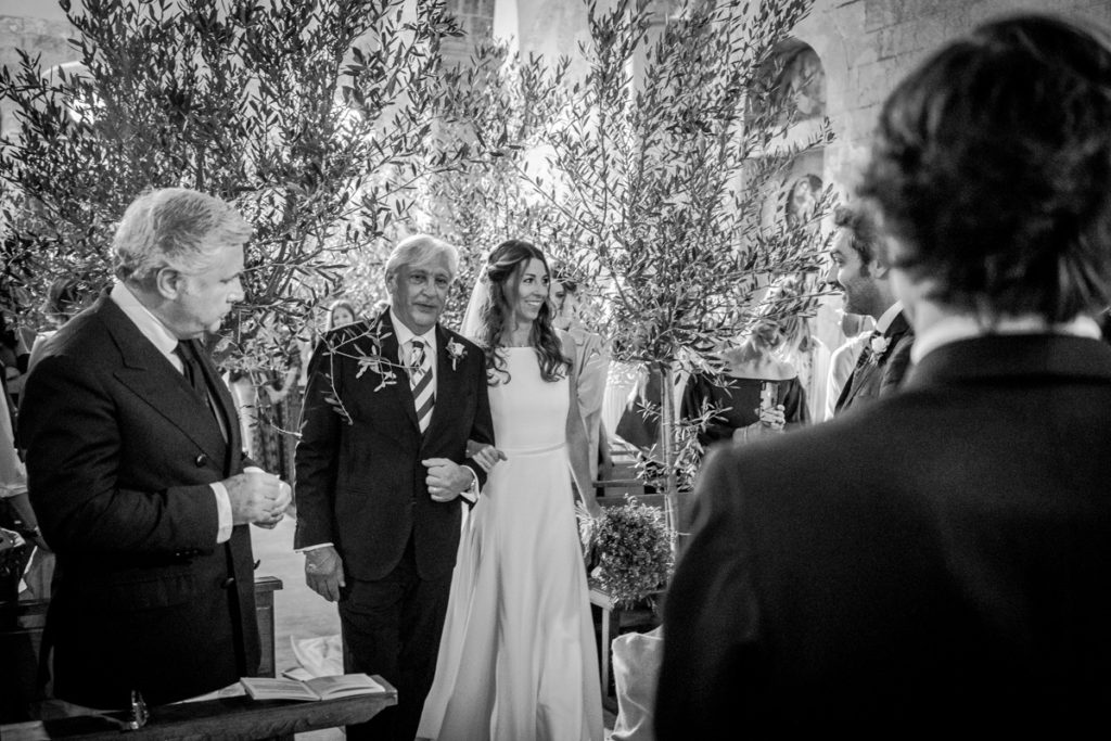wedding photographer padre accompagna la sposa altare tra ulivi