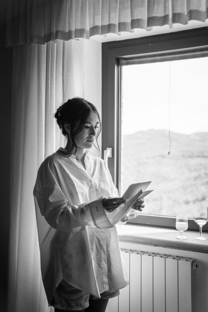 bride write an emotional  letter from the groom before the cerimony in front of the window