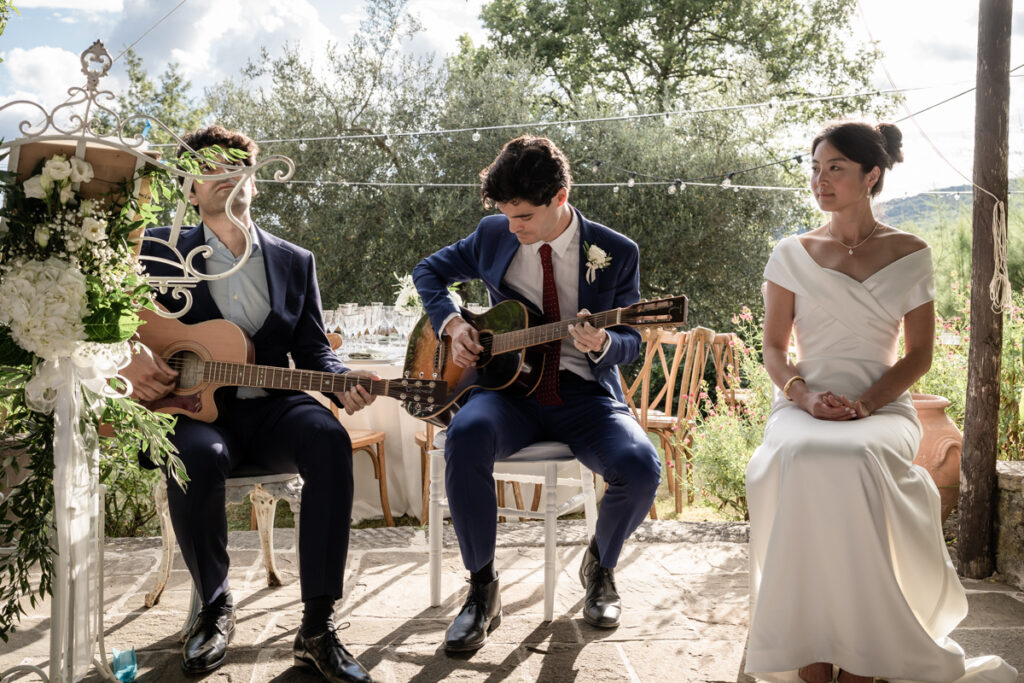intimate wedding photogrpaher in Tuscany countryside private villa between Tuscany and Umbria, italian style, groom plays guitar during the cerimoy